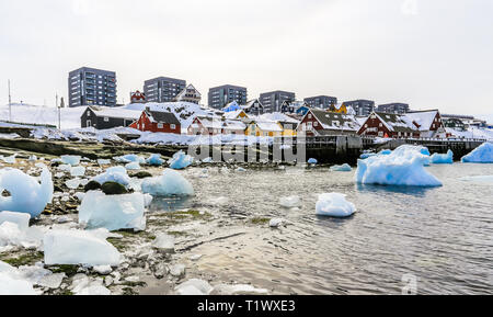 Moderne Gebäude und kleine Hütten mit Eisbergen in der Lagune treiben, Nuuk Hafen der Altstadt, Grönland Stockfoto