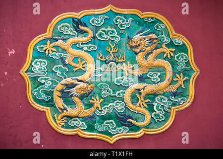 Zwei Drachen glasierte Fliesen- auf eine Rote Wand in Peking. Drachen sind wichtig in der buddhistischen kunst und Mythen Stockfoto