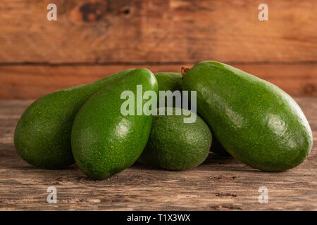 Stapel der ungeschälte helle grüne Avocados auf Holz rustikale Tabelle Stockfoto