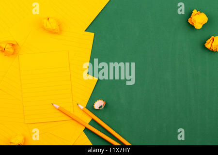 Eine orange Blatt Papier liegt auf einem grünen School Board bilden einen Rahmen für Text. in der Nähe von Stift und Zerknitterte Seiten. Kopieren raum Flache Ansicht von Oben Konz legen Stockfoto
