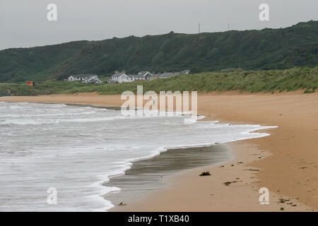 Weiße Wellen an Land kommen an einem Sandstrand in County Donegal, Irland. Person zu Fuß entlang Culdaff Strand. Stockfoto