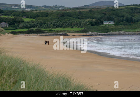 Drei Menschen zu Fuß entlang eines breiten Sandstrand mit weißen Wellen auf der Halbinsel Inishowen an Culdaff im County Donegal, Irland. Stockfoto