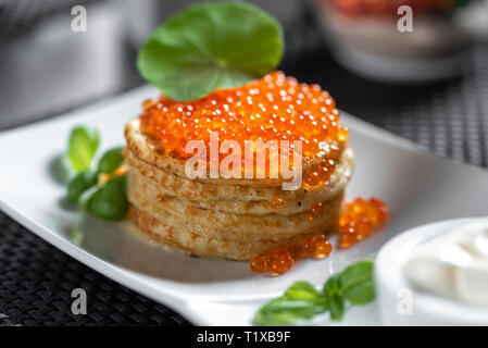 Pfannkuchen mit Kaviar im "russischen Stils" auf dunklem Hintergrund. Stockfoto