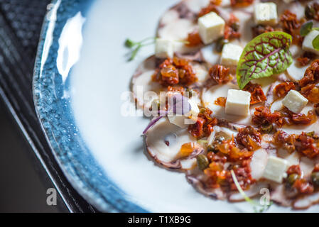 Carpaccio vom Oktopus auf blauen Platte Stockfoto