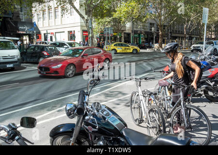 Australische Teenager Mädchen Frau sammelt ihr Fahrrad von einem Stellplatz auf dem Bürgersteig in der Innenstadt von Melbourne, Victoria, Australien Stockfoto