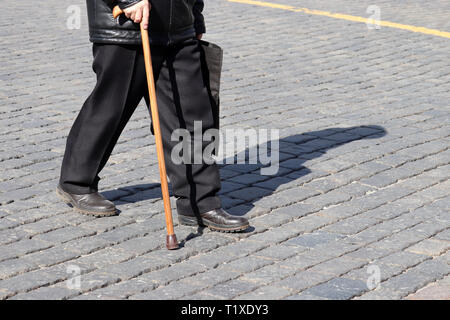 Alten Mann mit einem Stock auf die Straße. Konzept für Erwerbsunfähigkeit, Alter, humpelnde Person, Erkrankungen der Wirbelsäule, ältere Menschen Stockfoto