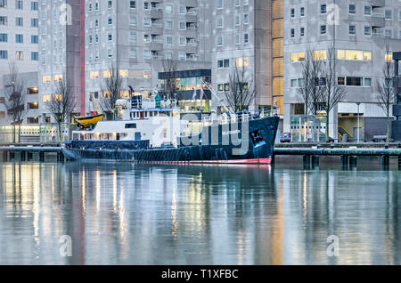 Rotterdam, Niederlande, 11. Januar 2019: ehemalige Wartung Schiff, vor Wohngebäude festgemacht, reflektiert in Leuvehaven Hafen in t Stockfoto