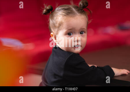 Close-up halbe Umdrehung Portrait von jungen Mädchen mit niedlichen Gesicht, mit schwarzen Shirt und ihre Hände auf dem Tisch, von der Kamera suchen Stockfoto