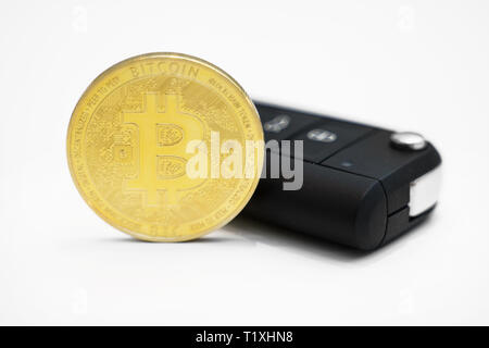 Golden physischen Bitcoin und Autoschlüssel auf weißem Hintergrund. Stockfoto