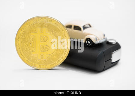 Golden physischen Bitcoin und Autoschlüssel auf weißem Hintergrund. Stockfoto