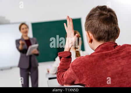 Rückansicht der Schüler heben die Hand während der Lektion im Klassenzimmer Stockfoto