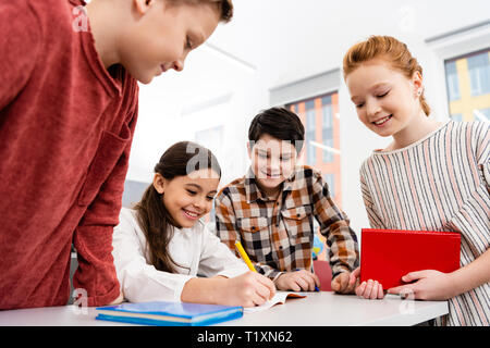 Lächelnd Schüler mit Notebook und Bücher Diskutieren im Klassenzimmer Stockfoto