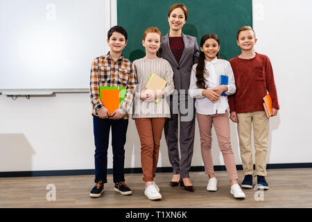 Lehrer und Schüler mit Notebooks Vor der Tafel stehend Stockfoto