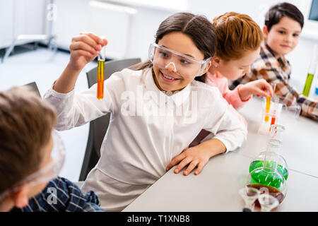 Schüler in der Schutzbrille holding Kolben während Chemie Lektion Stockfoto