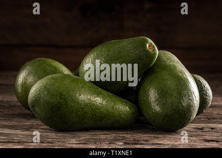 Stapel der ungeschälte helle grüne Avocados auf Holz rustikale Tabelle Stockfoto