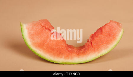 Die Hälfte gegessen Wassermelone Stück auf braunem Hintergrund isoliert Stockfoto