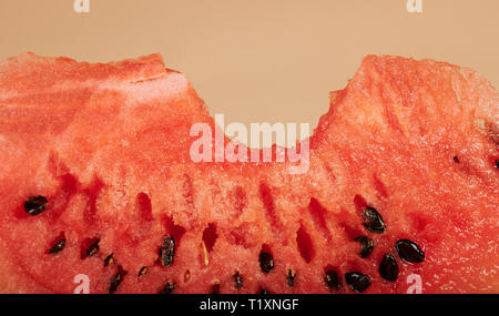 Ein Biss auf Wassermelone Stück makro Blick auf braunem Hintergrund Stockfoto