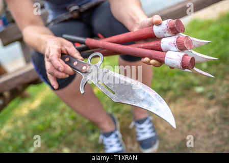 Frau mit wurfmesser und drei Achsen in ihre Hände Stockfoto