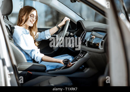 Junge Frau, die ein Smartphone vom Ort der drahtlose Aufladen in der modernen Autos in der Stadt Stockfoto