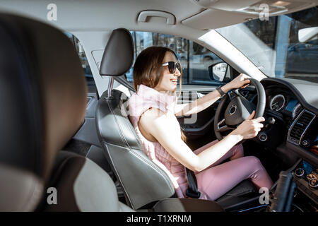 Junge und fröhliche Frau in Rosa sportswear Luxury Car Fahren in der Stadt nach der sportlichen Ausbildung Stockfoto