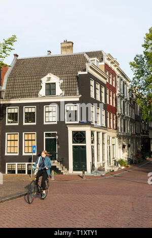 Ein Radfahrer fährt vorbei an typisch holländischen Häusern an der Kreuzung der Brouwersgracht Canal und der Keizersgracht in Amsterdam, Niederlande. Stockfoto
