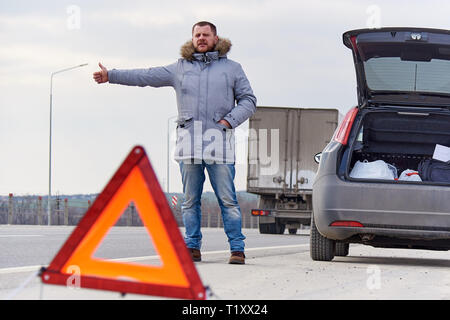 Junger Mann per Anhalter auf der Straße Stockfoto