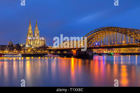 Ein abendlicher Blick auf den Kölner Dom über den Rhein, mit der Hohenzollern Eisenbahnbrücke im Vordergrund, Köln, Deutschland Stockfoto