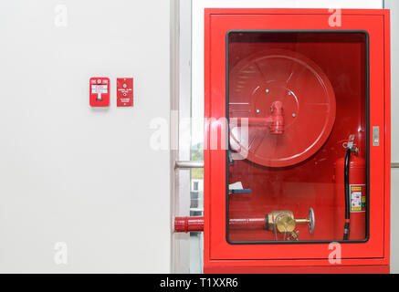 Feuerlöscher und Löschschläuche Haspel hängen an der Wand in Gebäude, Sicherheitskonzept Stockfoto