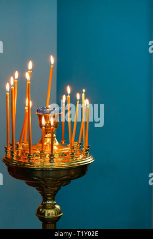 Runde Leuchter mit brennenden Kerzen auf dem Altar in der christlichen Kirche Stockfoto