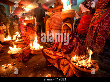 Hinduistische Frauen gesehen mit brennenden Feuer Töpfe auf den Kopf wie ein traditionelles Ritual der Verehrung Devi Sheetala sitzt. Nach der hinduistischen Mythologie Devi sheetala wird als sie heilt die Pocken, Wunden, Ghouls, Pusteln und Krankheiten verehrt. Daher hinduistischen Menschen beobachten schnell für den ganzen Tag und dabei verschiedene traditionelle Praktiken wie Dandi (liegend auf dem Boden) und brennenden Feuer Topf auf dem Kopf, während der Anbetung zu Devi sheetala für Wertsteigerung ihrer Familienmitglieder. Stockfoto