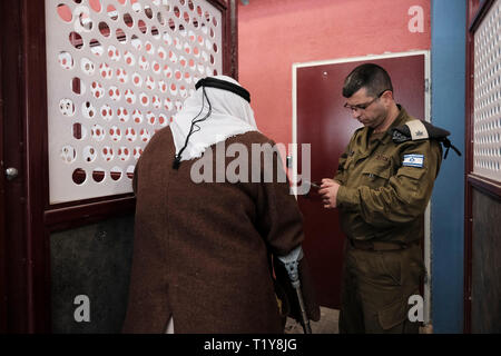 Kalandya, ISRAEL 28.. März - ein älterer Palästinenser, der am 28. März 2019 am Grenzübergang Kalandia oder Kalandiya zwischen Jerusalem und Ramallah von einem israelischen Militäroffizier überprüft wurde. Die $11 Millionen Renovierung des Qalandiya Checkpoint wurde durchgeführt, um die Pendelanbahnung von Tausenden von Palästinensern täglich zu verbessern, hauptsächlich mit Hilfe neuer Identifikationsstationen mit verbesserter Technologie. Kredit: Eddie Gerald/Alamy Live Nachrichten Stockfoto