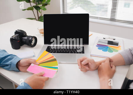Zwei Fotografen mit Kamera und Laptop arbeiten im Büro Stockfoto