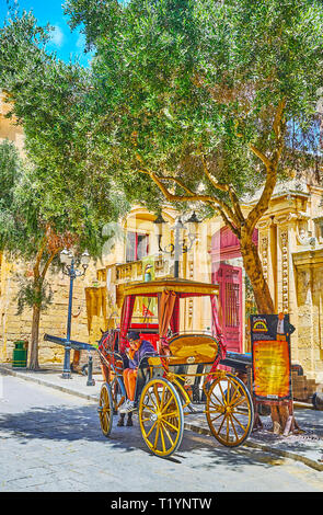 MDINA, MALTA - 16. Juni 2018: Die vintage Beförderung in St Publius Platz im Schatten der Bäume geparkt Neben Vilhena Palace, am 16. Juni in Mdina. Stockfoto