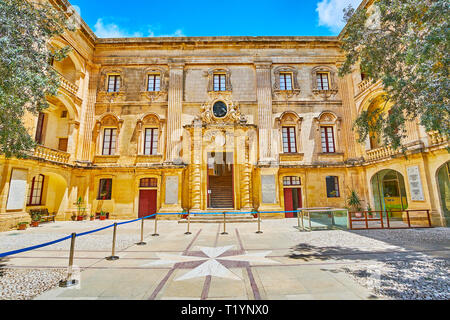 MDINA, MALTA - 16. Juni 2018: Die reich verzierte Fassade des mittelalterlichen Vilhena (behördliche) Palast mit geschnitzten Verzierungen und Malteserkreuz auf dem Boden in Fr Stockfoto