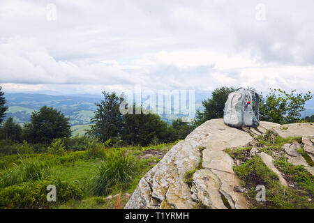 Grau Rucksack mit einem Kunststoff Flasche Trinkwasser auf einem Berg gegen den Berg Landschaft Hintergrund Stockfoto