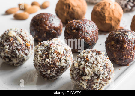 Hausgemachte Energie beißt, vegane Schokolade Trüffel mit Nüssen, Kakao und Kokosraspeln. Konzept und gesundes Essen. Close Up. Stockfoto