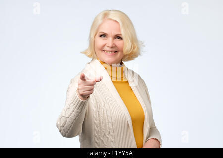 Freundliche ältere Frau zeigt mit dem Finger auf Kamera. Studio schießen. Positive facial Emotion Stockfoto