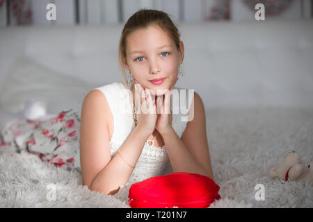 Sehr schöne jugendlich Mädchen liegt auf einem Bett mit ein rotes Herz Kissen. Die junge Dame Stockfoto