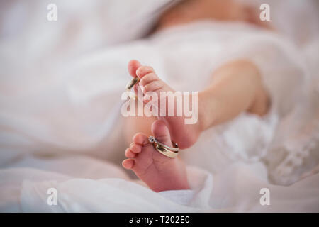 Close up baby Füße mit Trauringe auf die großen Zehen. Stockfoto