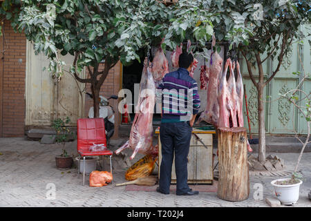 Kunden, die Lammfleisch zu einem Metzger in Kashgar (Provinz Xinjiang, China) kaufen Stockfoto