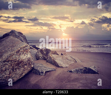 Einen malerischen Sonnenuntergang über einem felsigen Strand, Farbe getonte Bild. Stockfoto