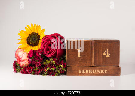 Happy Valentine's Day vintage Holz- Ewiger Kalender für Februar 14 isoliert auf weißem Hintergrund und ein Bündel von verschiedenen Blumen Stockfoto