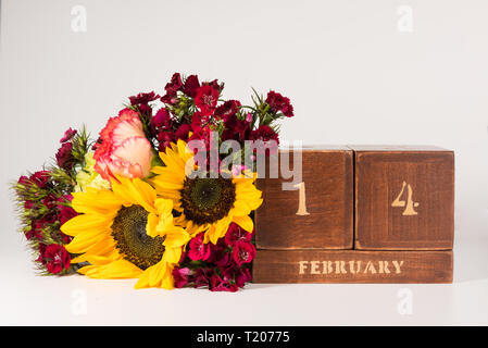 Happy Valentine's Day vintage Holz- Ewiger Kalender für Februar 14 isoliert auf weißem Hintergrund und ein Bündel von verschiedenen Blumen Stockfoto