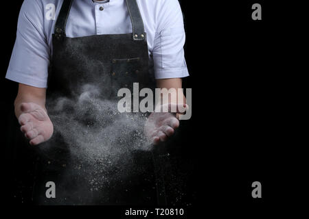 Hände und Mehl im Splash baker klatschen auf schwarzem Hintergrund Stockfoto