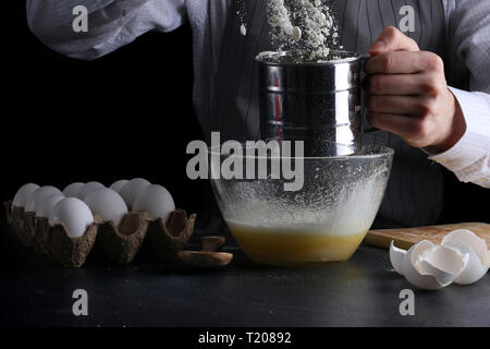 Sichten Mehl in Schüssel. Mann kochen Dessert Konzept. Stockfoto