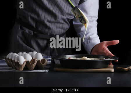 Gießen kuchen Teig in eine Backform. Mann halten Schüssel und Gießen Teig. Stockfoto