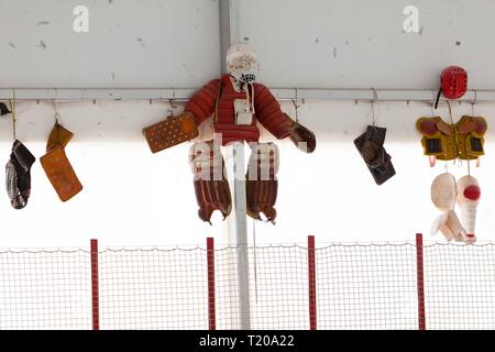 Alte schützende Hosen und andere torhüter Schutz an der Wand hängen im Eishockey Stadion. Stockfoto