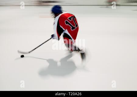 Allein die jungen Hockeyspieler im roten Kleid mit der Nummer 17 in Bewegung, verschwommene Bewegung auf dem Eis Stadion, Zug wie Star Stockfoto