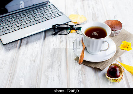 Herbst noch leben. Tea Party Herbst Tag Tasse Kaffee, Kuchen, Nüsse, Blätter, Blumen, Brille und Laptop. Kopieren Sie Platz. Stockfoto