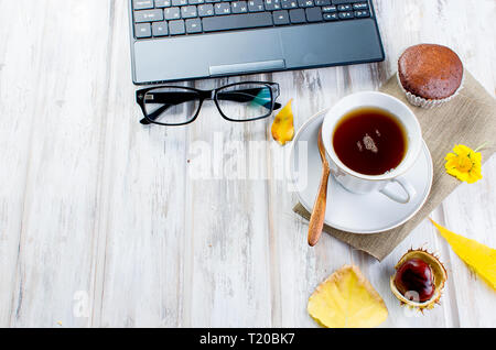 Herbst noch leben. Tea Party Herbst Tag Tasse Kaffee, Kuchen, Nüsse, Blätter, Blumen, Brille und Laptop. Kopieren Sie Platz. Stockfoto